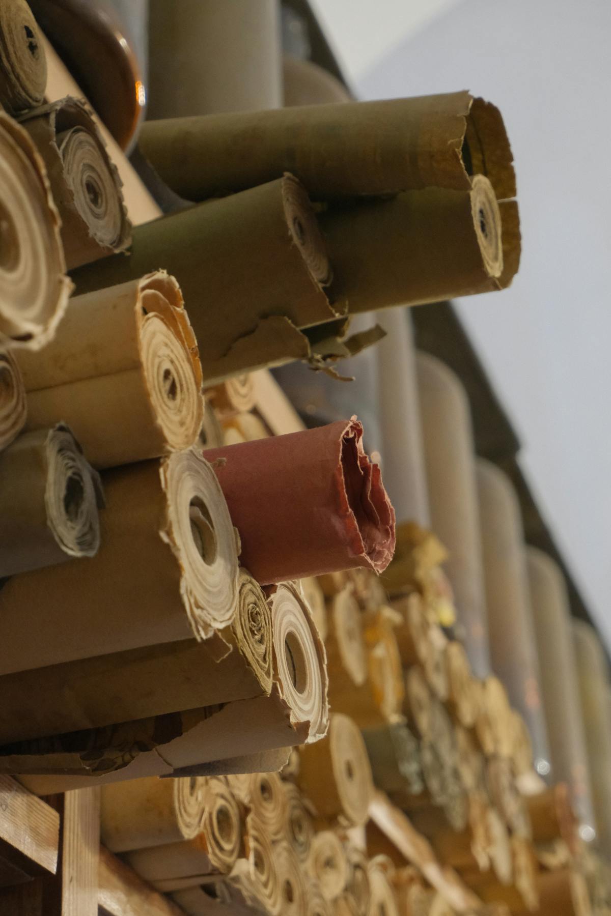Stacked rolls of patterned fabric arranged on textile shelves.